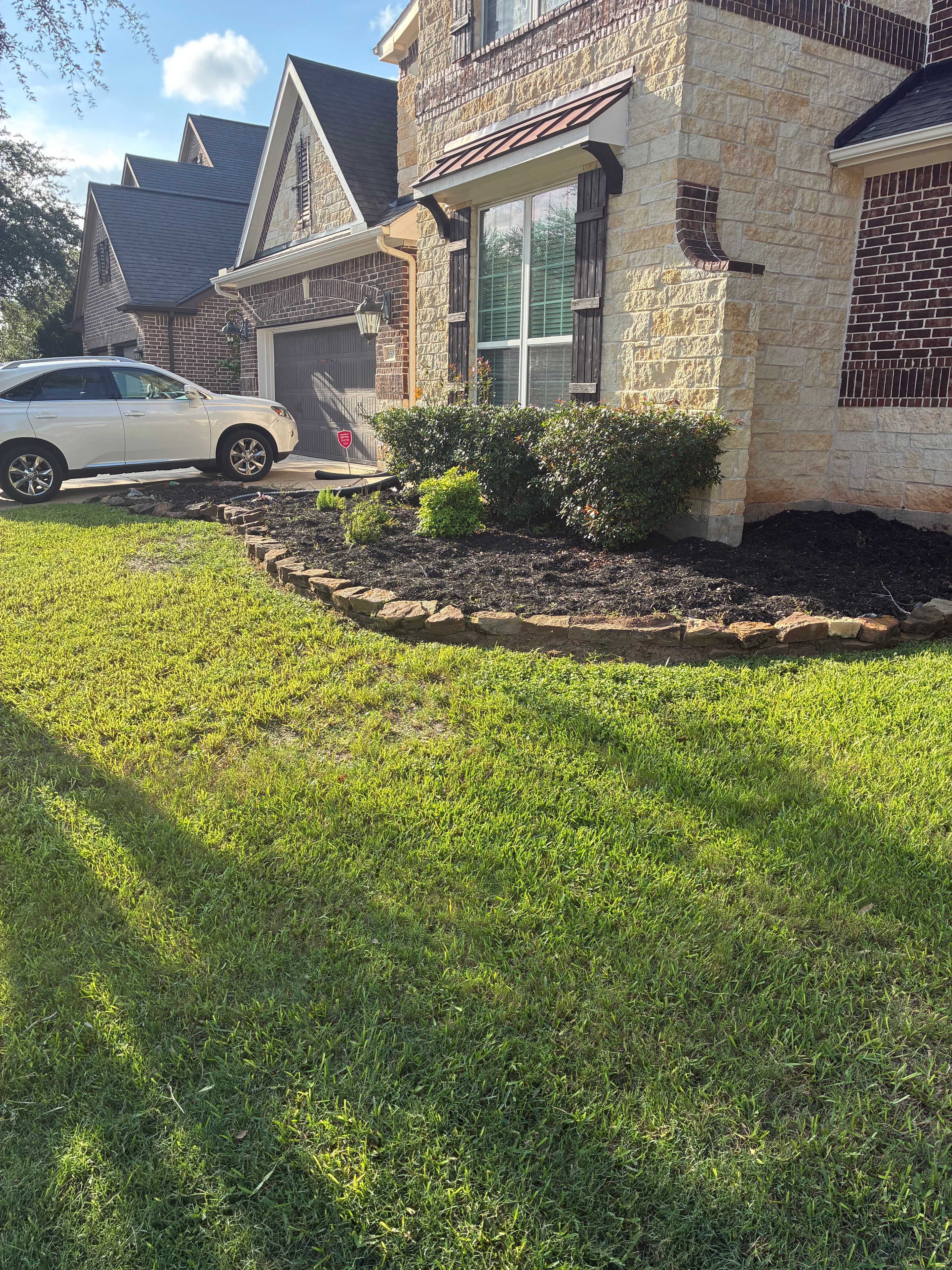 Stone home with trimmed garden bed and manicured lawn